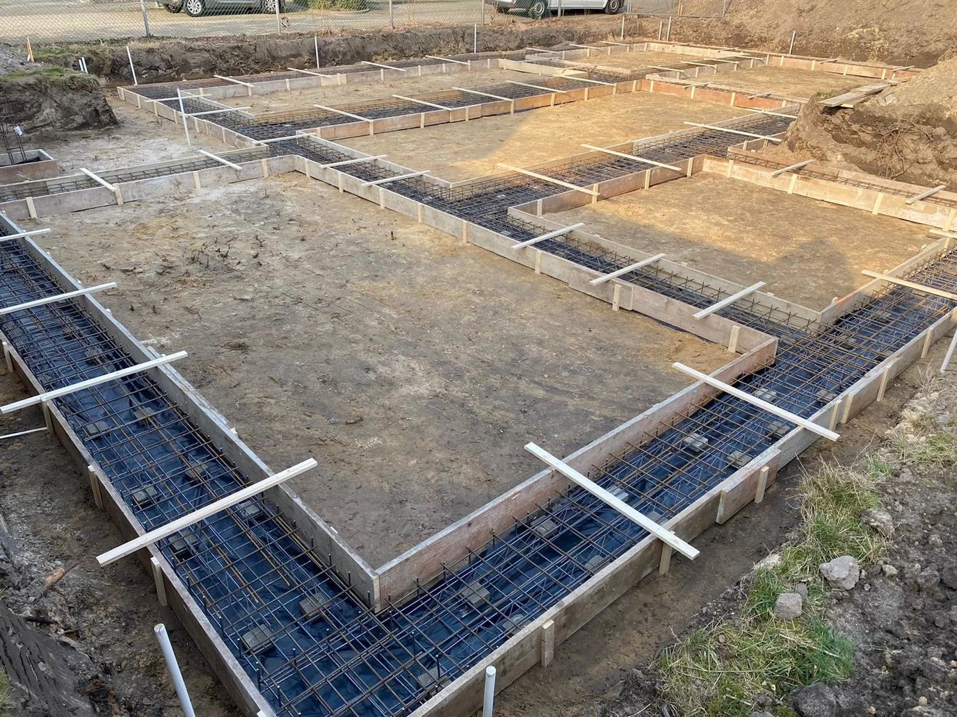 Bekisting en wapening van een strokenfundering, uitgezet op de bouwkavel